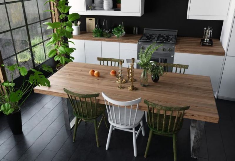 Kitchen with a reclaimed wood dining table, mismatched spindle chairs and potted greenery