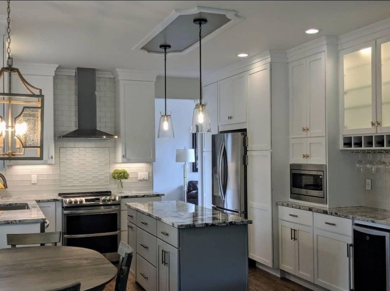 White shaker kitchen with a gray island, marble counters and glass pendant lights
